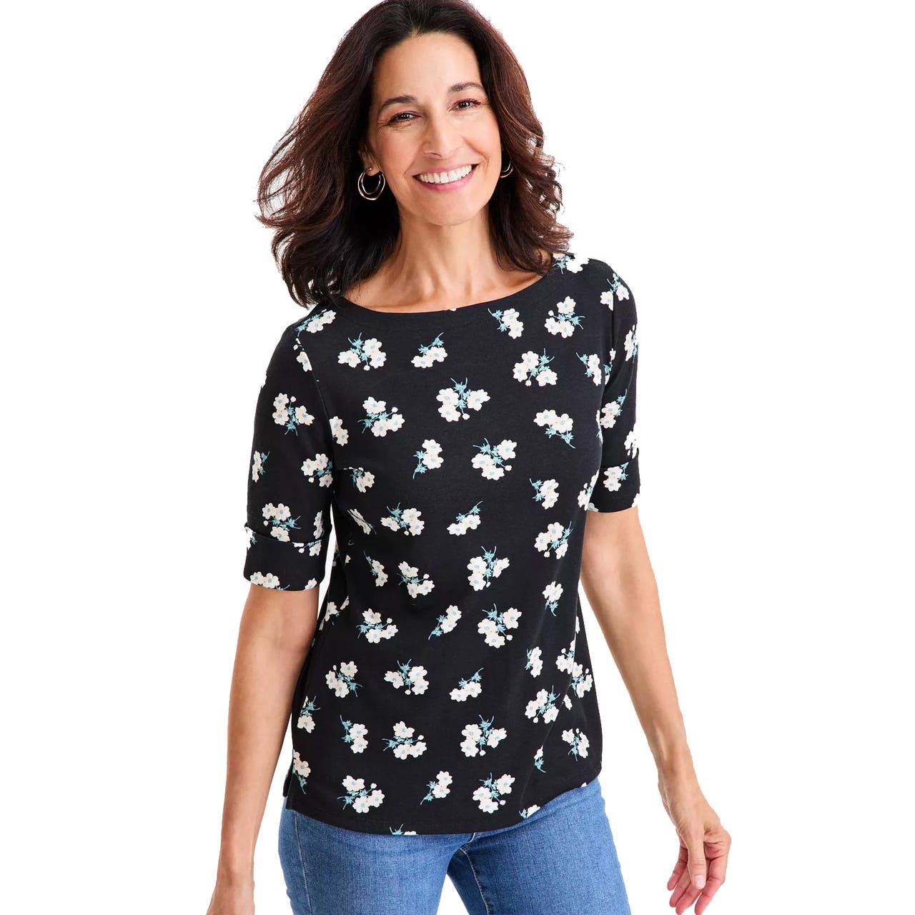 A woman is wearing a black top with small white flower patterns and short sleeves, paired with blue jeans.