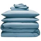 A neatly stacked set of blue bedding, including two pillows, a duvet, and folded sheets, all arranged in a compact pile.