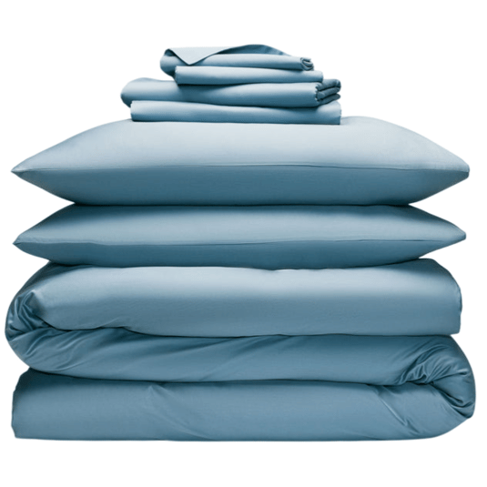 A neatly stacked set of blue bedding, including two pillows, a duvet, and folded sheets, all arranged in a compact pile.