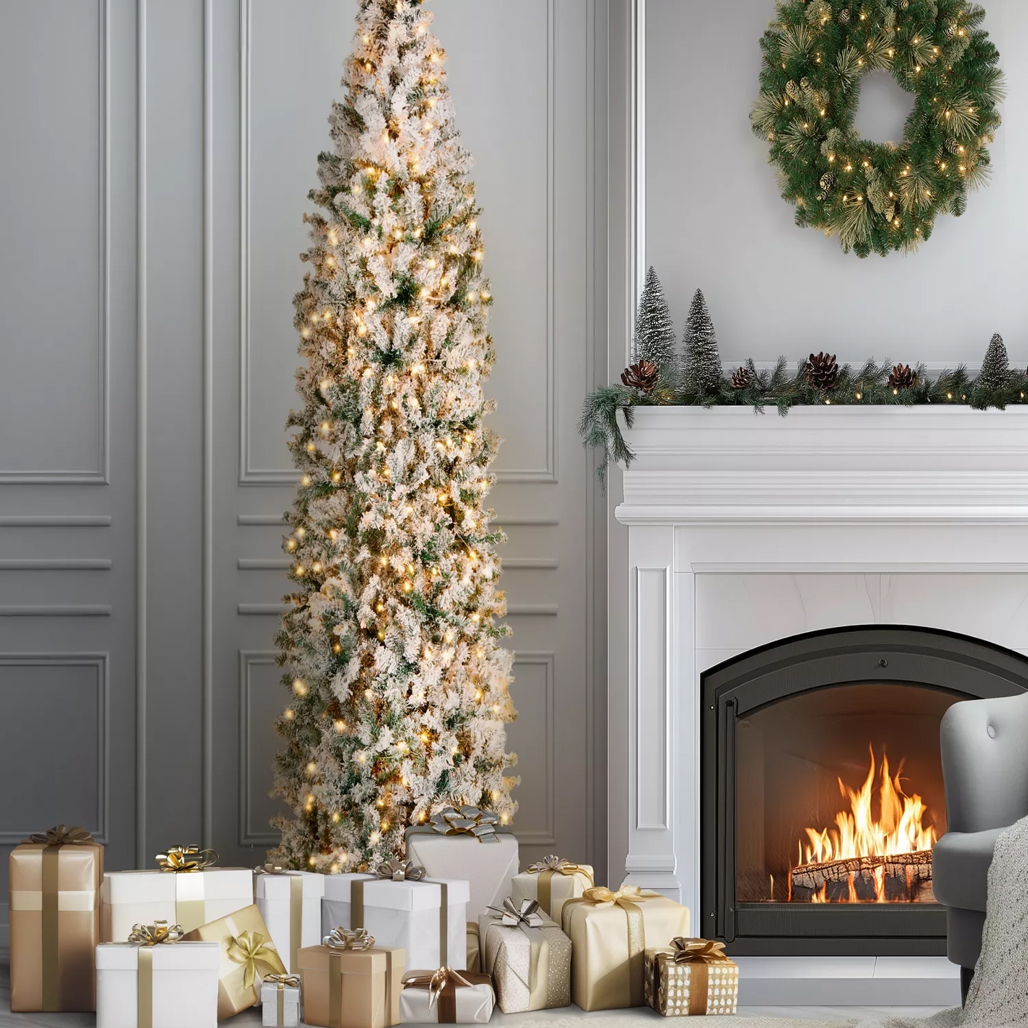 A tall, slim, flocked Christmas tree with warm lights is surrounded by gold and silver wrapped gifts. A decorated fireplace with a wreath, miniature trees, pinecones, and garland enhances the cozy holiday setting.