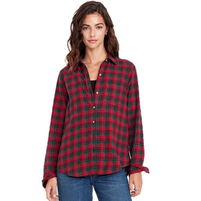 A woman is wearing a red and green plaid button-up shirt over a black top, paired with blue jeans.