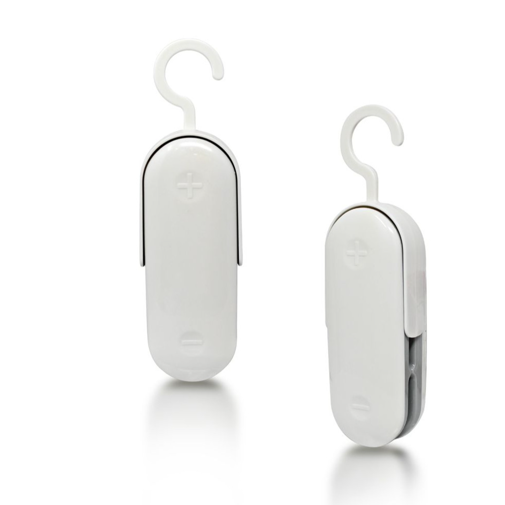Two white hanging dehumidifiers with hooks, designed to reduce moisture in small spaces. Each unit has a simple design with a plus and minus symbol on the front.