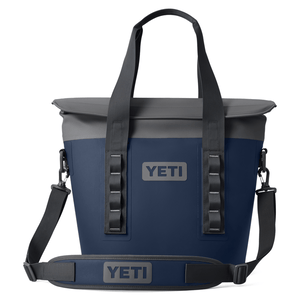 A navy blue and gray YETI cooler bag with a shoulder strap and sturdy handles, featuring the YETI logo on the front.
