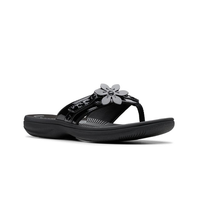 Clarks Breeze Opal Sandals are black with a glossy finish, featuring a flower decoration on the strap and a comfortable cushioned sole.