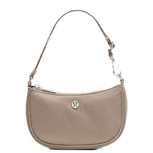 A small, beige shoulder bag with a short strap and a silver logo on the front.