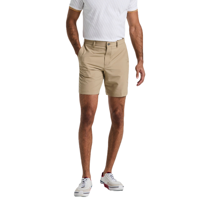 A man is wearing a white short-sleeve polo shirt, beige shorts, and white sneakers with red accents.
