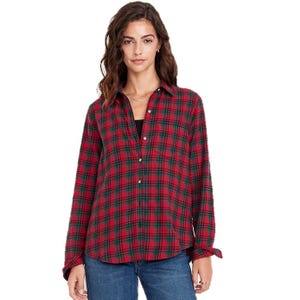 A woman wearing a red and green plaid button-up shirt with long sleeves, paired with blue jeans.