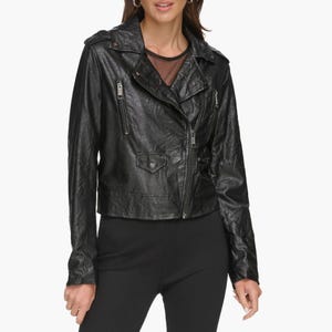 A woman is wearing a black washed faux-leather moto jacket with asymmetrical zipper closure and multiple zippered pockets.