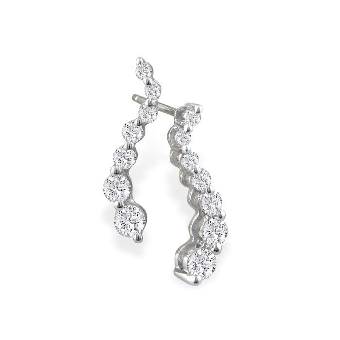 A pair of silver ear climber earrings featuring a curved line embellished with round, clear gemstones.