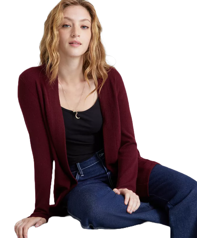 A woman wears a burgundy cashmere duster sweater over a black top and blue jeans. The cardigan is long, open-front, and has a soft, luxurious texture.