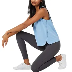 A person is kneeling while wearing a light blue sleeveless top, dark gray leggings, and white sneakers.