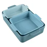 A set of three nested baking dishes in varying shades of blue, featuring rectangular and square shapes with built-in handles.