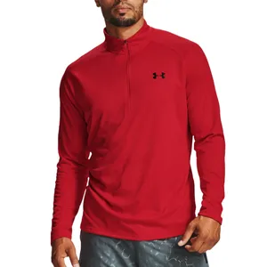 A red long-sleeve Under Armour quarter-zip shirt is worn by a person paired with gray-patterned shorts.
