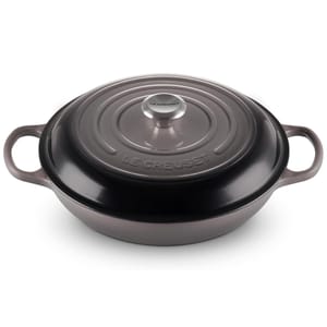 Round, enameled cast iron casserole dish from Le Creuset with a lid, featuring two handles and a glossy finish.