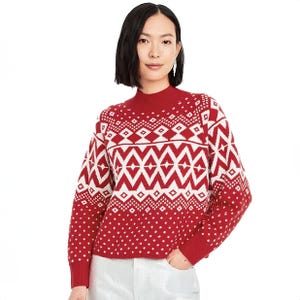 A model is wearing a red and white Fair Isle patterned sweater with a crew neck and long sleeves.