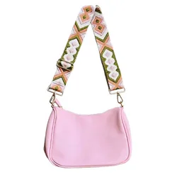 Pink handbag with a colorful, patterned, adjustable strap featuring geometric designs in green, pink, and white.