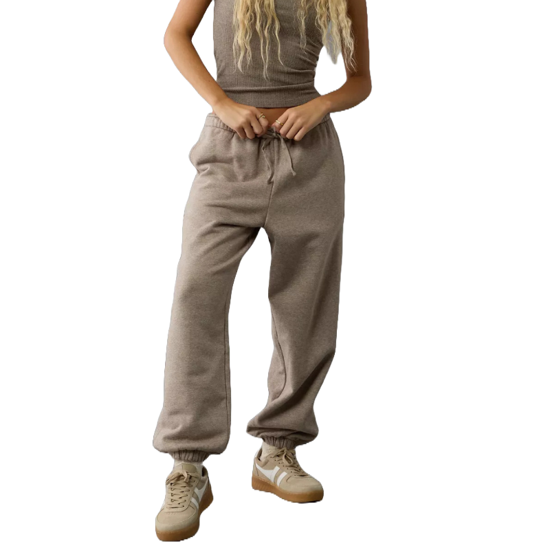 A person wearing taupe-colored sweatpants and beige sneakers, paired with a textured sleeveless top.