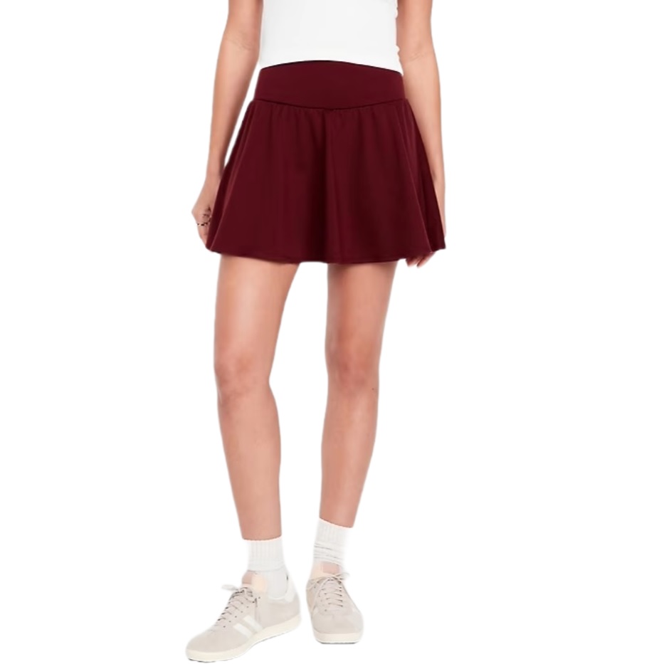 A person is wearing a maroon skirt and white sneakers with socks. The background is white.