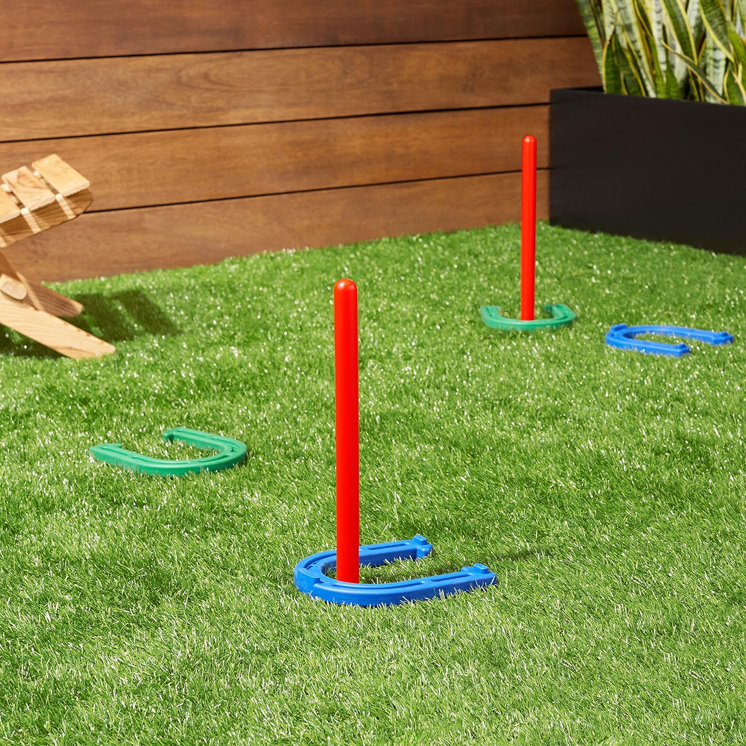 A ring toss game with red posts and blue and green rings on artificial grass.