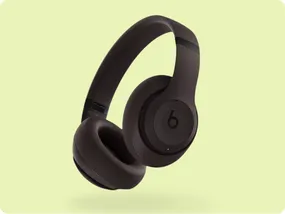 Dark brown over-ear wireless headphones with a prominent \“b\“ logo on the earcup against a light green background.