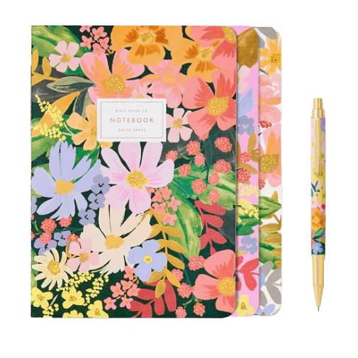 A colorful desk gift set featuring two floral-patterned notebooks and a matching pen. The notebooks display vibrant flowers in various colors, creating a lively and coordinated look with the pen.