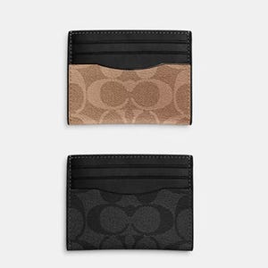 Two Coach card cases in black, one with a beige logo pattern and the other with a gray logo pattern.