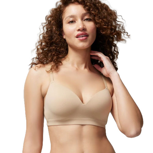 A woman wearing a beige, seamless bra with thin straps, designed for a smooth and comfortable fit.