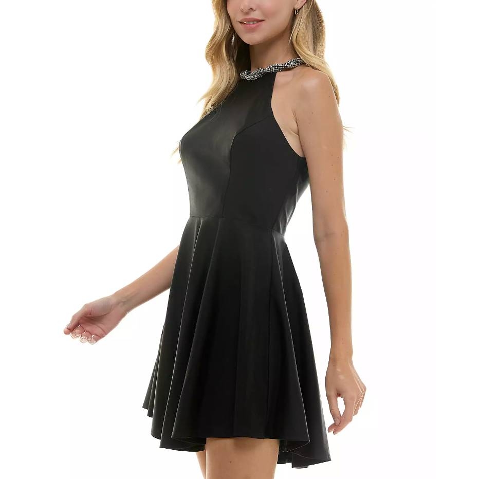 A woman in a sleeveless black skater dress with a halter neck and a pleated skirt.