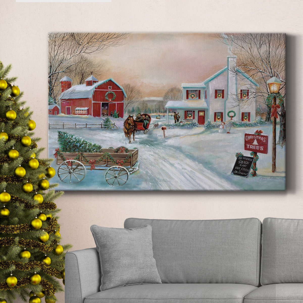 Canvas wall art depicting a snowy Christmas scene with a horse-drawn sleigh, a red barn, a white house, and a \“Christmas Trees\“ sign; situated above a gray couch next to a decorated Christmas tree.