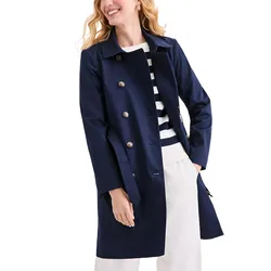 A woman is wearing a navy blue double-breasted coat over a striped sweater and white pants.