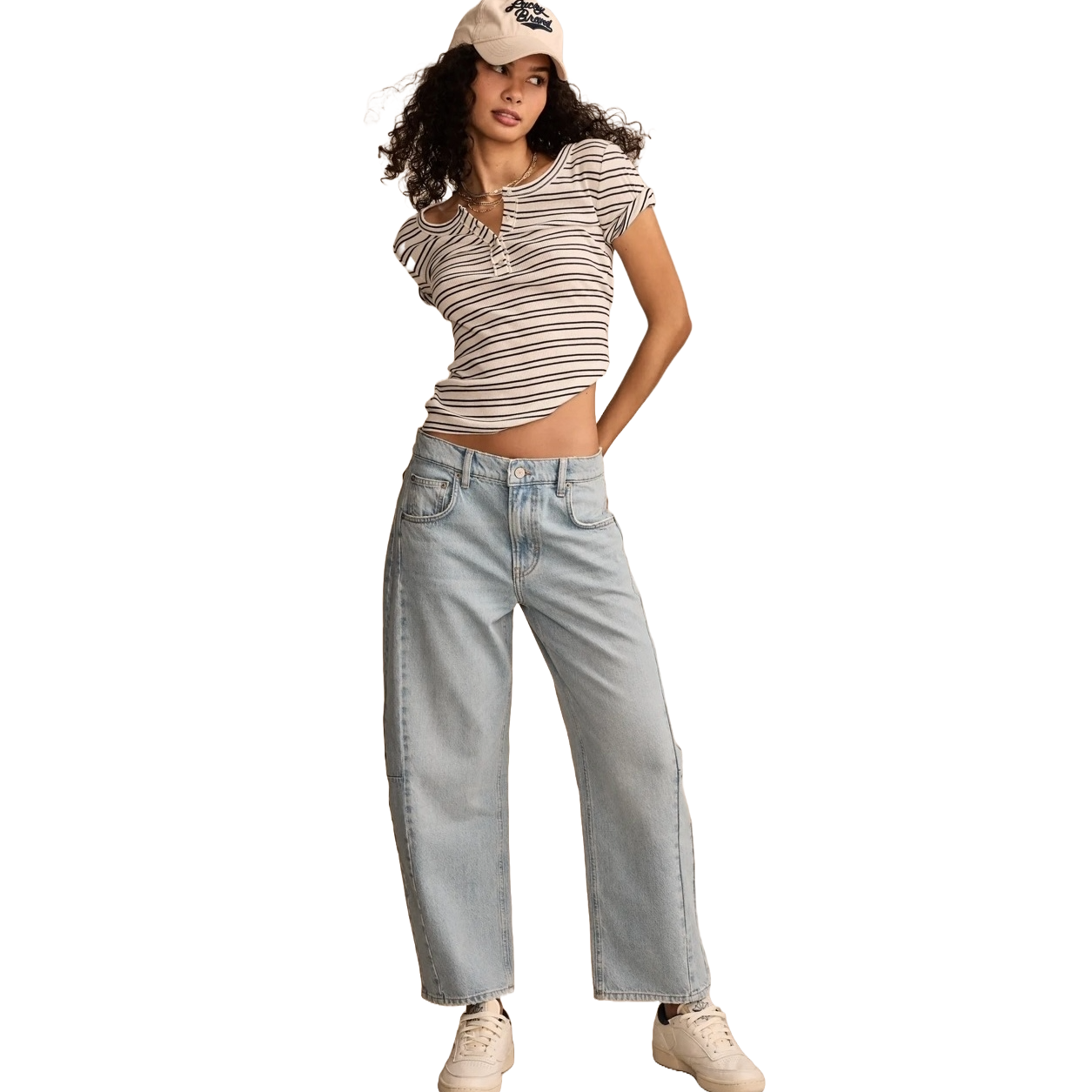 A person is wearing a striped top, light-wash wide-leg jeans, white sneakers, and a beige baseball cap.