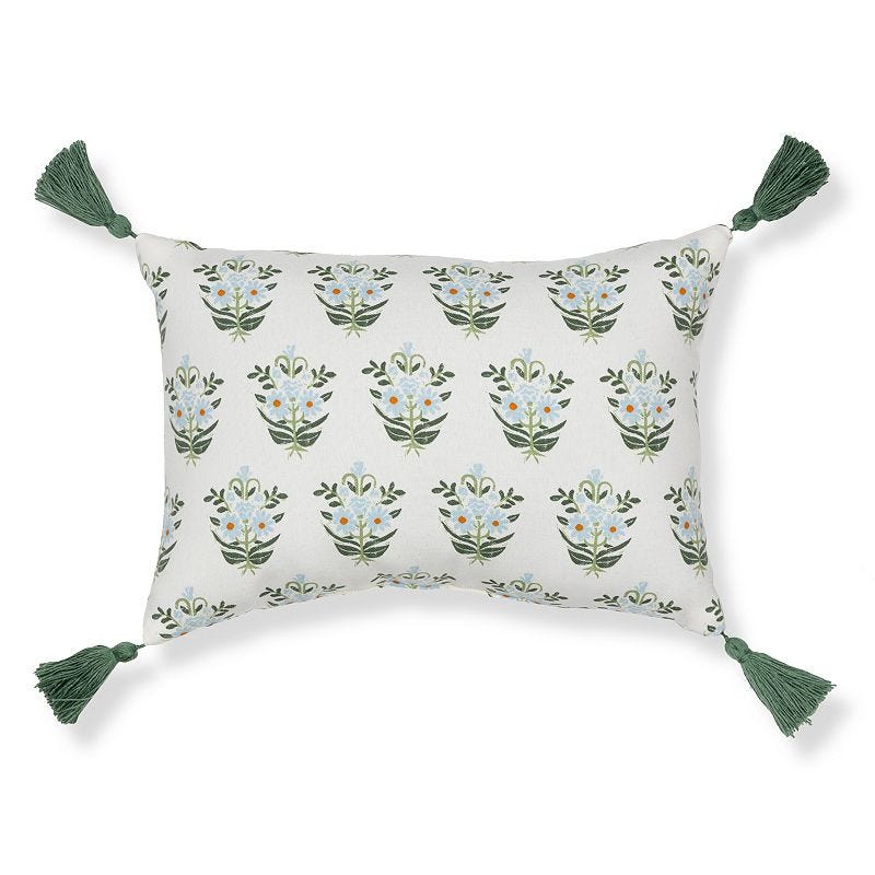 Rectangular throw pillow with a floral pattern and green tassels on each corner.