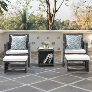 Outdoor furniture set with two wicker chairs, white cushions, patterned accent pillows, and a matching side table with decorative items.