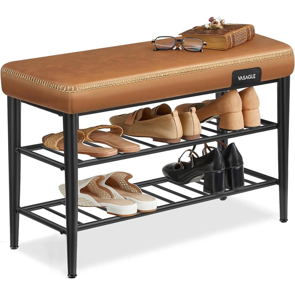 A brown cushioned bench with the brand name \“VASAGLE\“ features two metal racks for shoe storage, holding various pairs of shoes. On top, there are eyeglasses and a book.