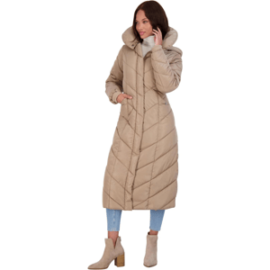 A woman is wearing a long, tan quilted coat with a large collar, paired with light blue jeans and beige heeled ankle boots.