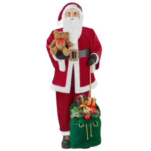 A 5-foot plush Santa Claus figure stands with a teddy bear in one hand and a green sack filled with presents in the other. Santa wears a red suit, black belt, and holds gold-detailed accessories.
