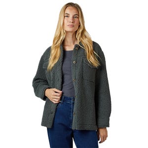 A woman is wearing a dark green sherpa fleece jacket over a gray top and blue jeans.