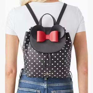 A polka-dotted backpack with a mouse ears and bow design on the top.