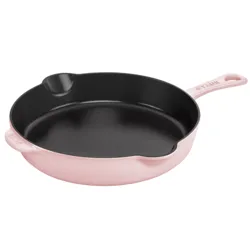 A pink enameled cast iron frying pan with a black interior, featuring a handle and two pour spouts.