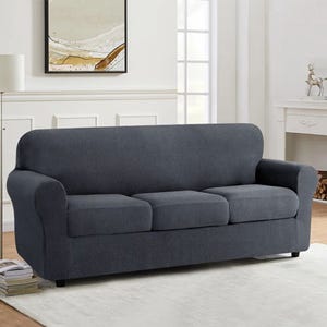 Gray, soft stretch sofa slipcover with a textured fabric design, fitting a three-seat couch in a modern living room setting with neutral decor.
