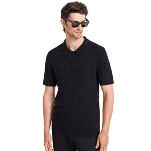 A man is wearing a black textured short-sleeve polo sweater with a zip-up collar, paired with sunglasses.