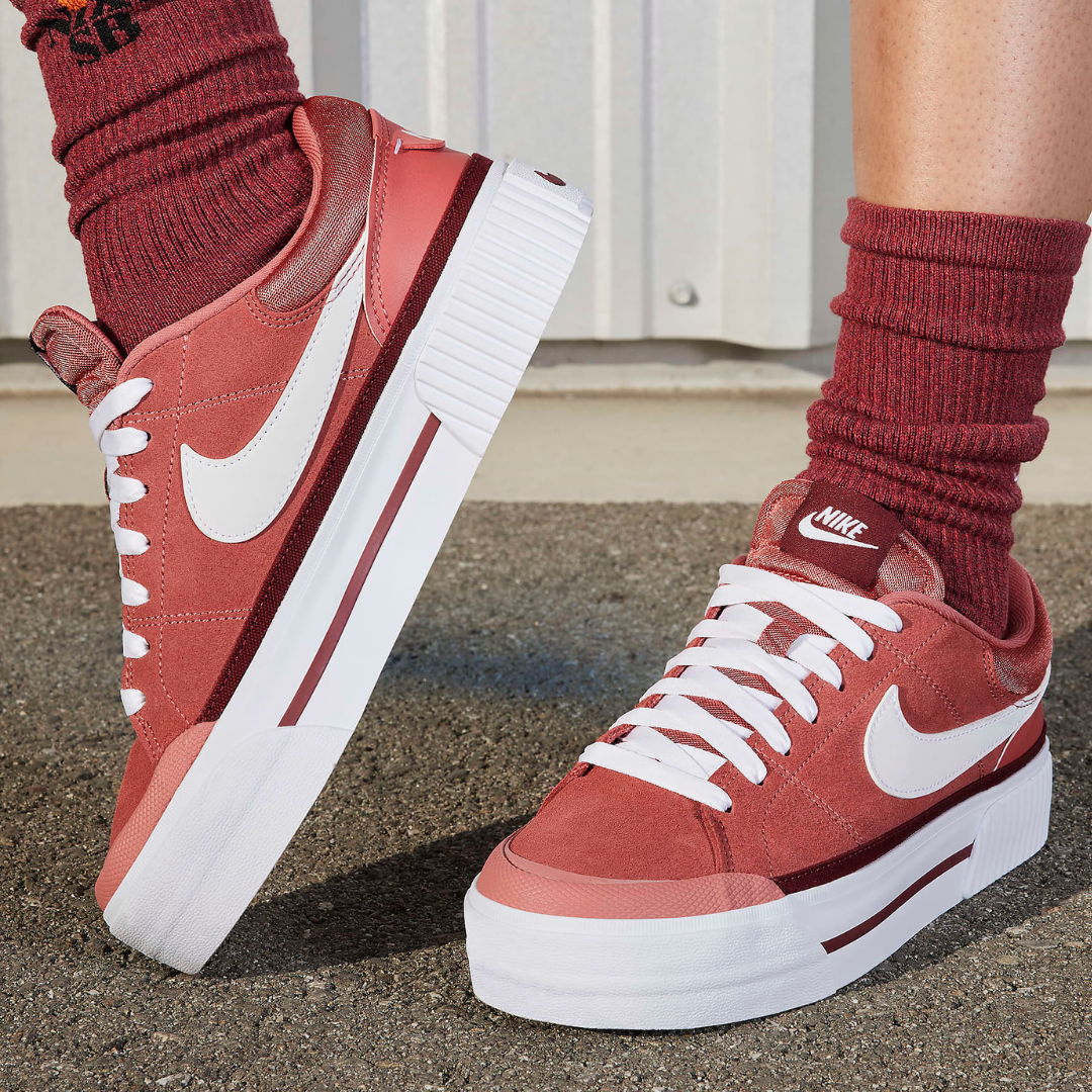 A pair of red and white sneakers with a high sole profile, alongside matching red socks.