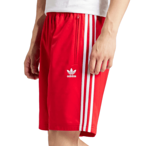 A person is wearing red Adidas shorts featuring white stripes and the Adidas Trefoil logo on the side.