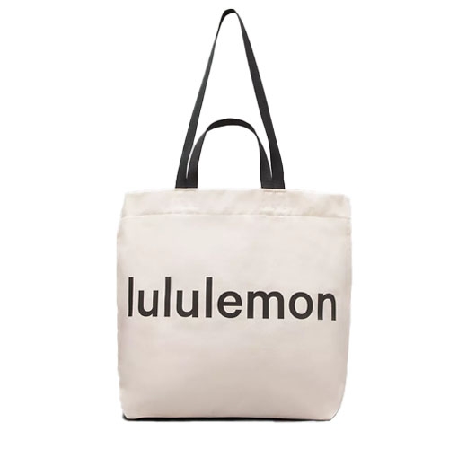 A beige tote bag with the \“lululemon\“ logo in black letters featuring two black straps.