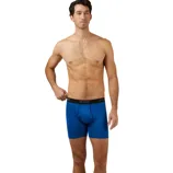 A man modeling in bright blue boxer briefs with a black elastic waistband labeled \“32° COOL.\“