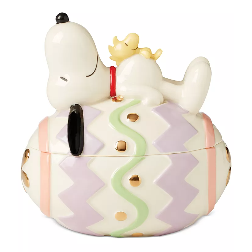 Lenox Snoopy Easter Candy Dish features Snoopy and Woodstock resting on a pastel and gold-dotted Easter egg. The dish doubles as a decorative piece and functional candy holder.
