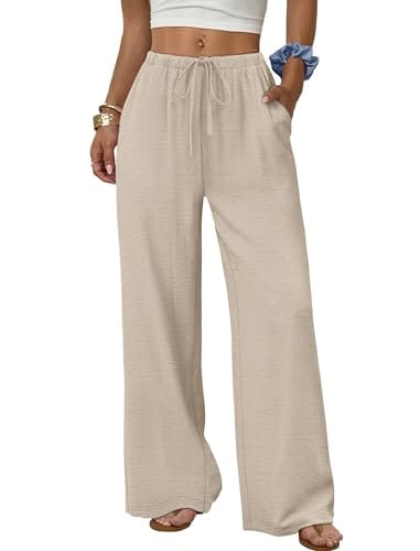 A person wears loose-fitting beige wide-leg pants with an elastic waistband and drawstring, paired with a white crop top and sandals.
