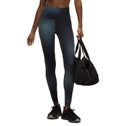 A person wears high-waisted leggings and black sneakers, carrying a black gym bag.