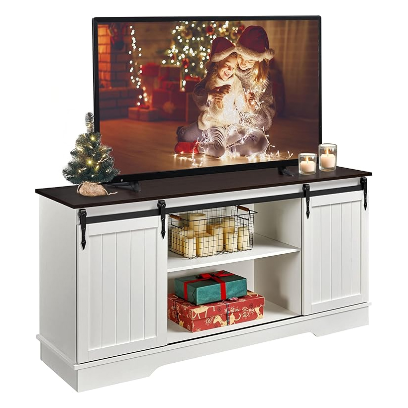 White farmhouse-style TV stand with sliding barn doors, open shelving, and a dark top, displaying a TV and decorated with holiday items.
