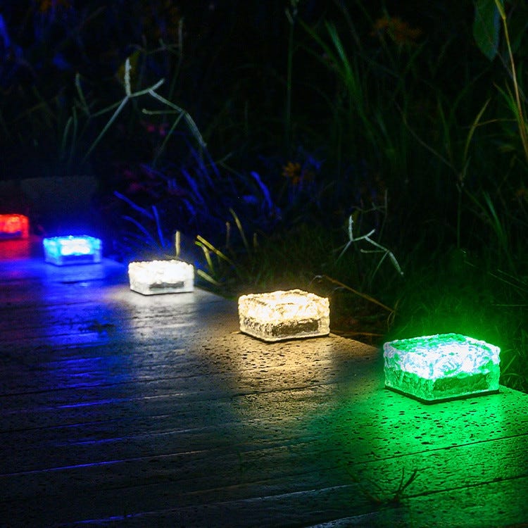 Solar-powered LED garden lights on a pathway, with multicolored illumination.